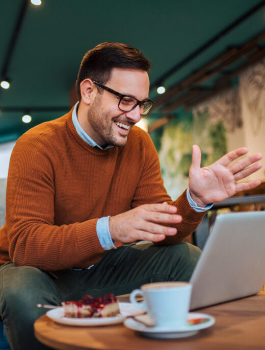 Handsome smiling man having video call on laptop in the cafe.
